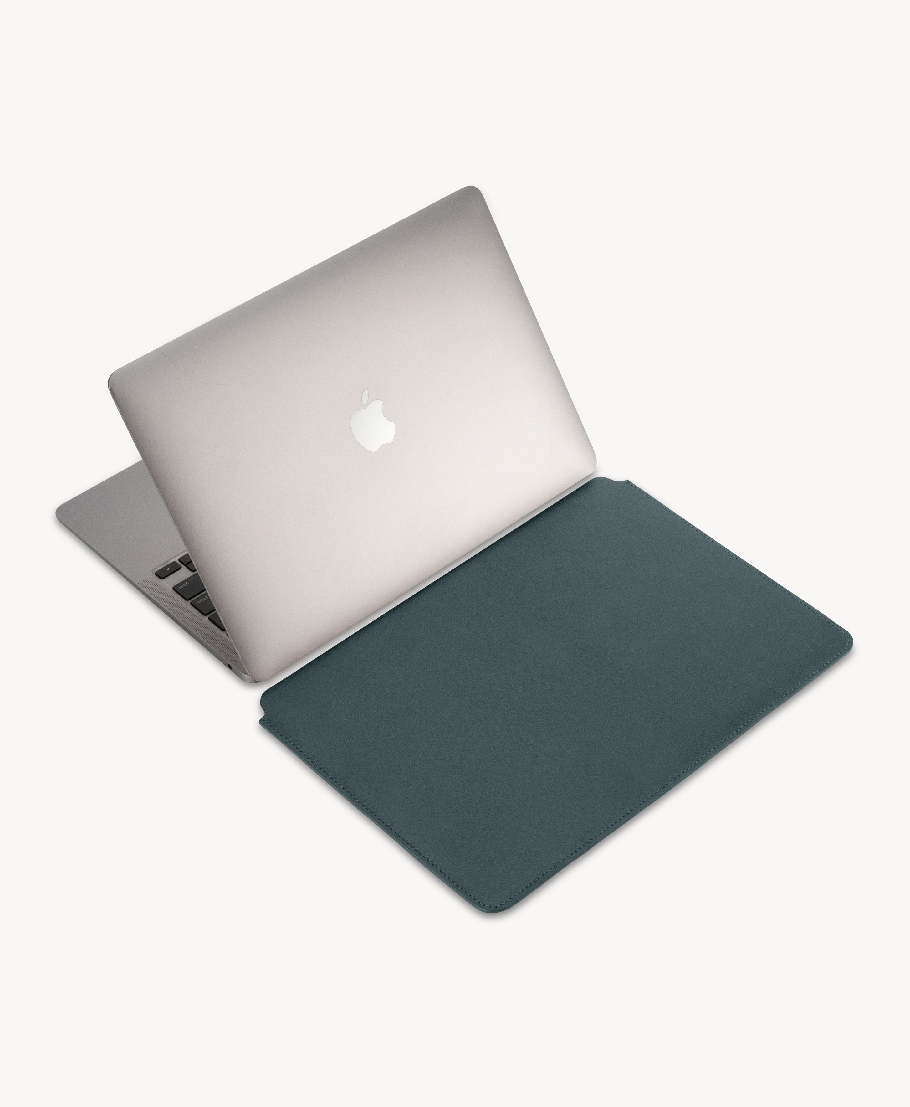 Blue full grain saddle leather laptop sleeve, beside an open MacBook