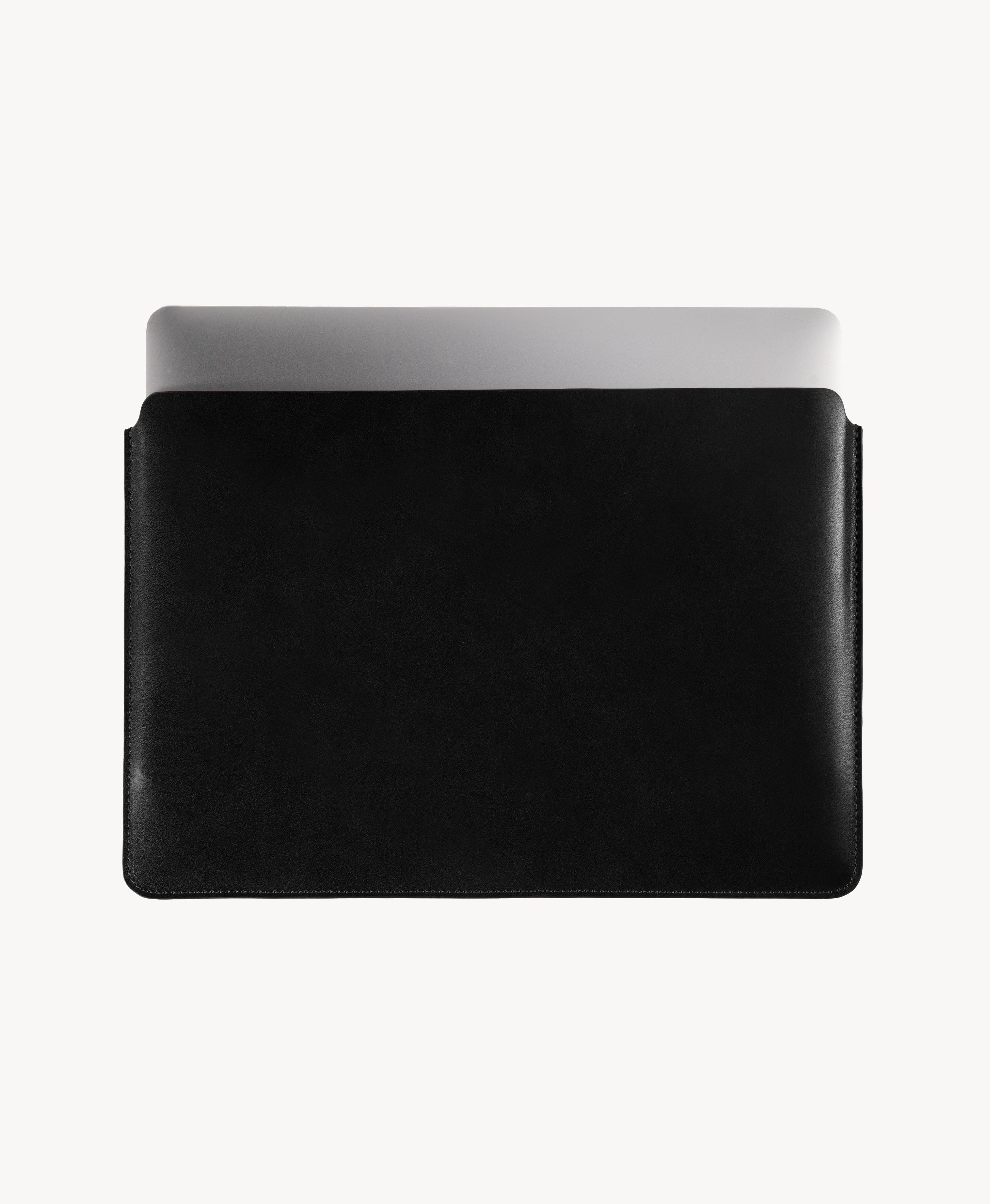 Black full grain saddle leather laptop sleeve, MacBook partially inserted through the open top