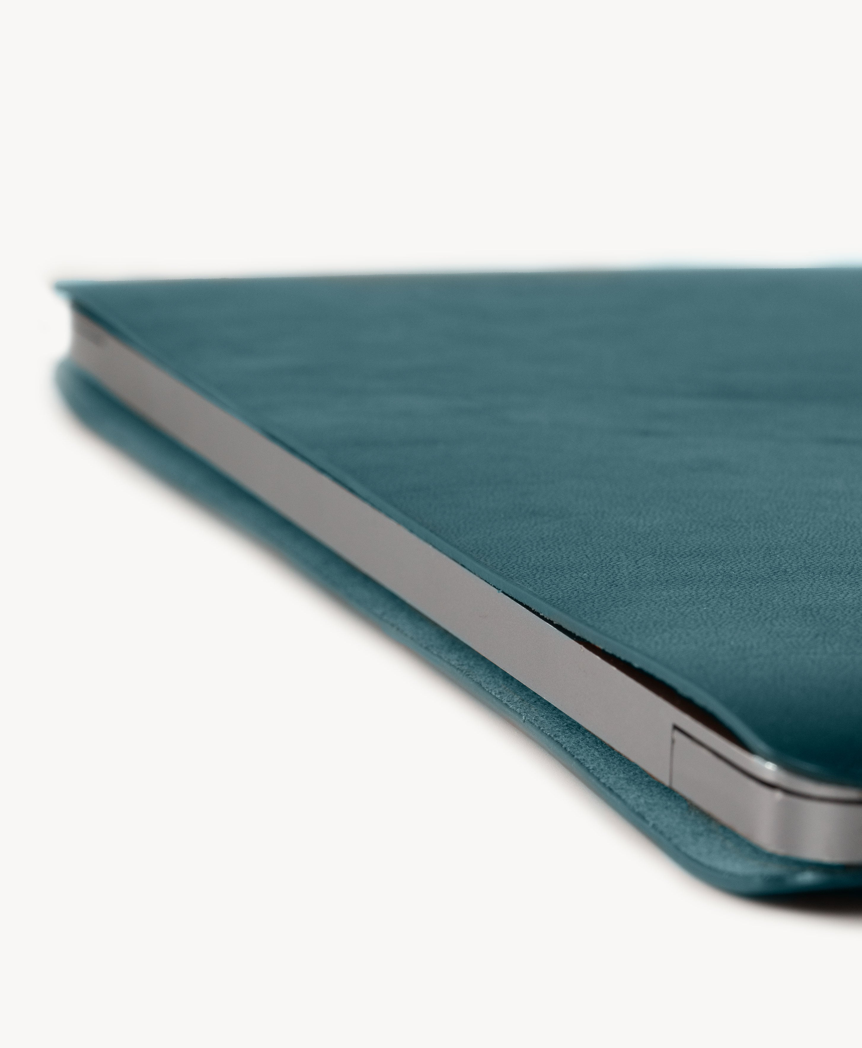 Blue full grain saddle leather laptop sleeve, slim side profile with a MacBook inserted
