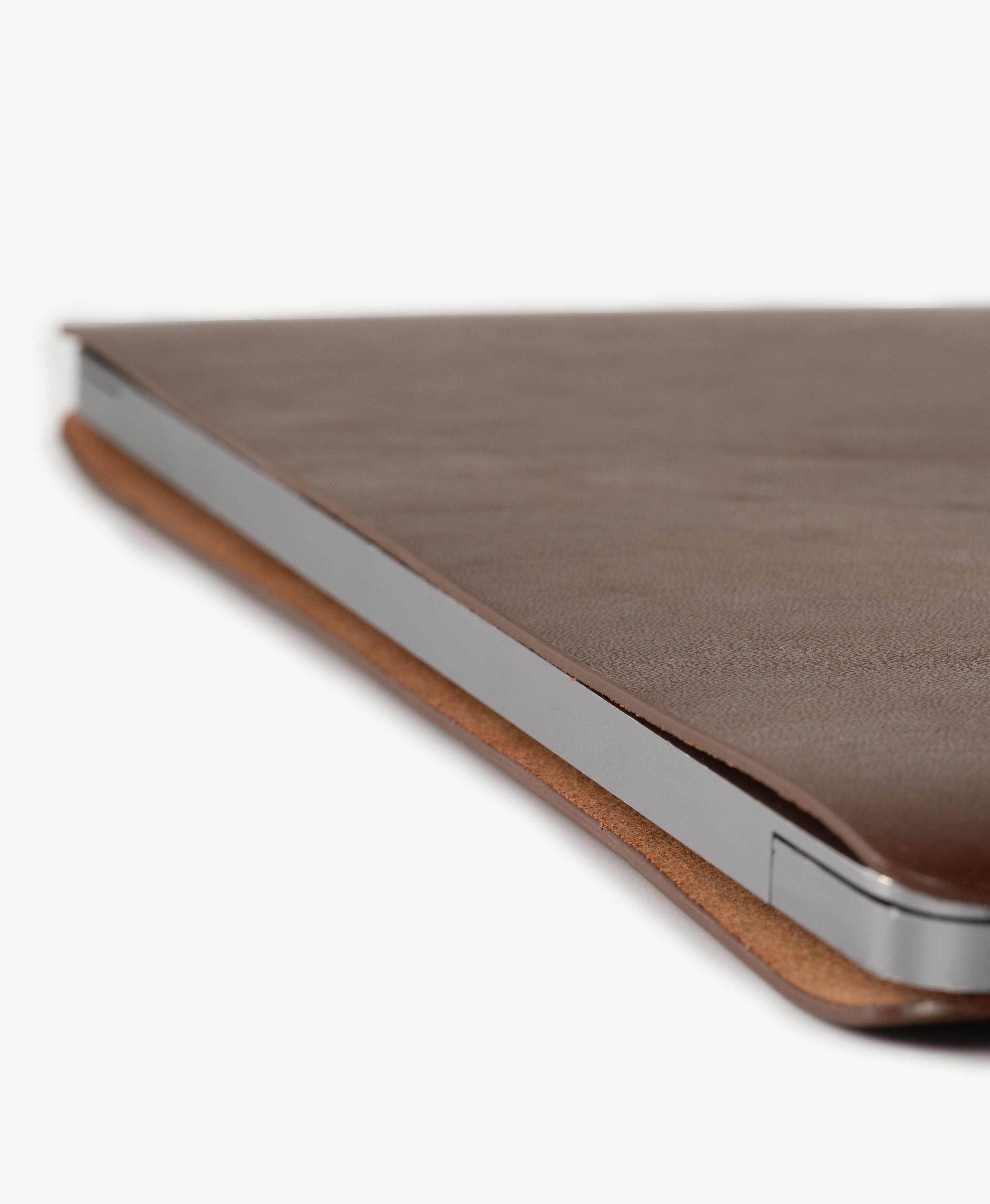 Brown full grain saddle leather laptop sleeve, slim side profile with a MacBook inserted