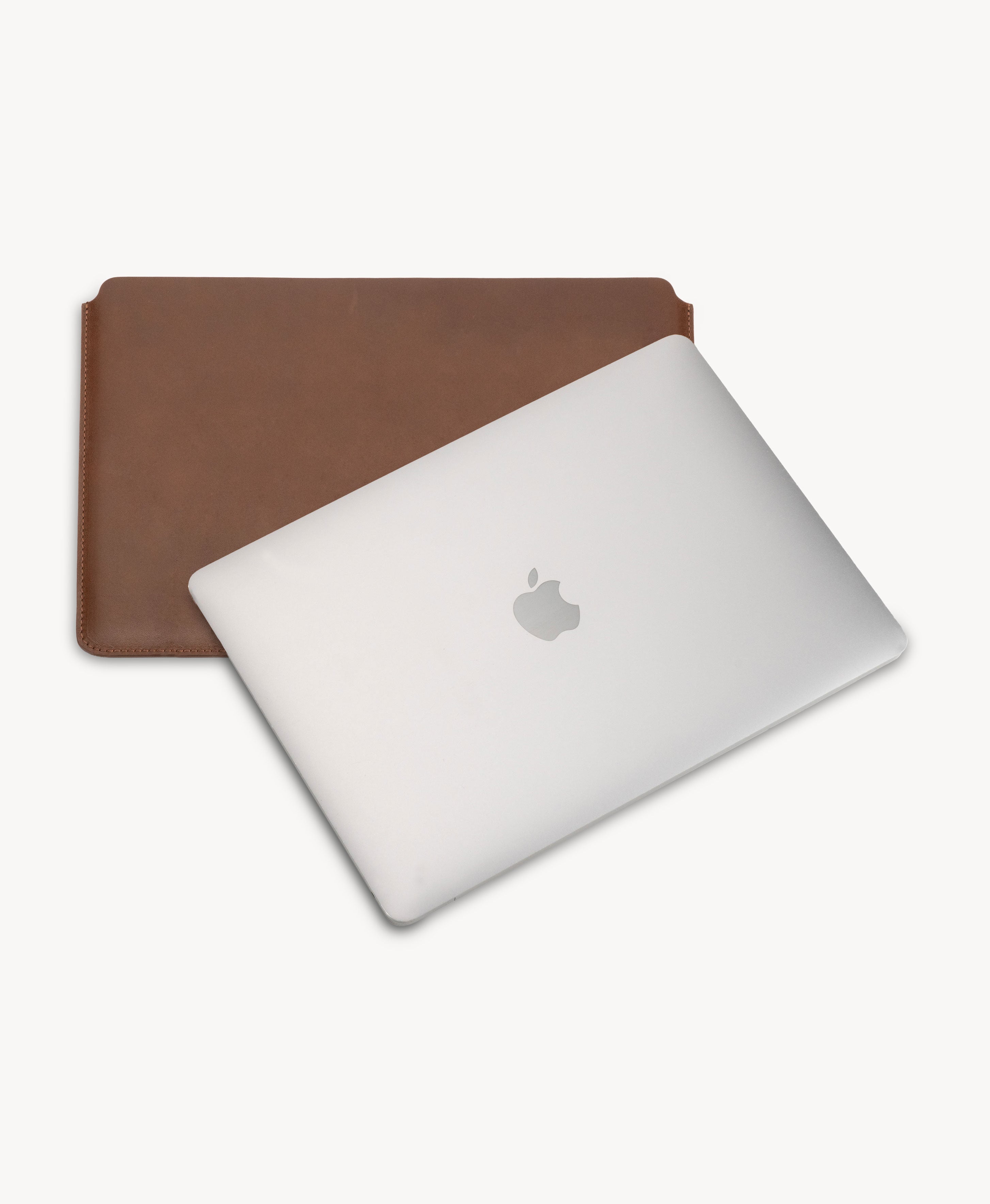 Brown full grain saddle leather laptop sleeve, shown with a MacBook